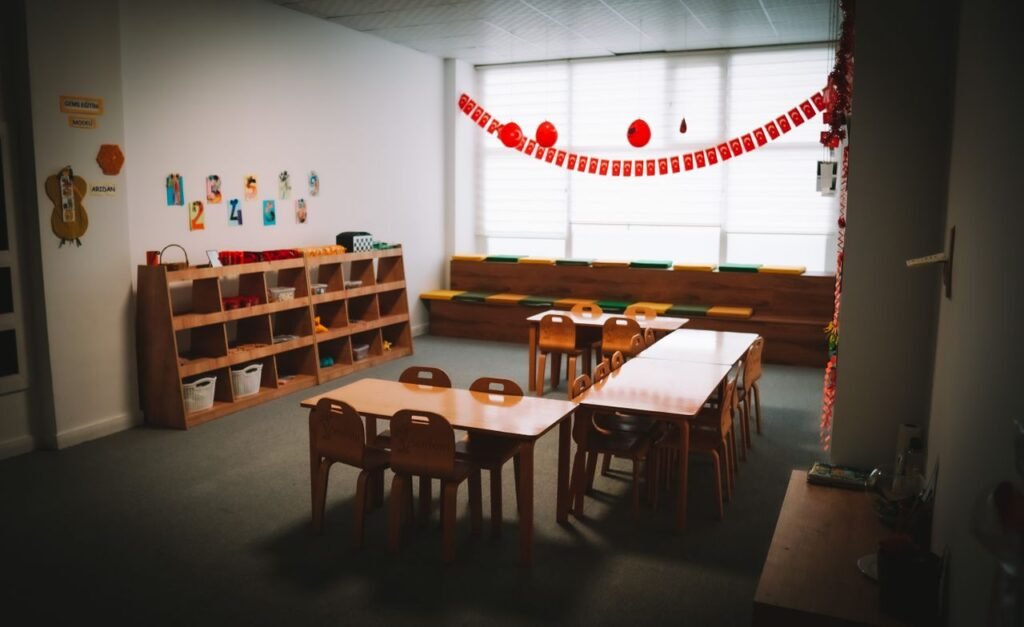 Home Inviting kindergarten classroom with tables, chairs, and colorful decorations, fostering a welcoming learning environment.