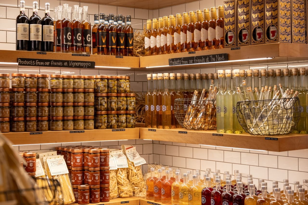 Home A vibrant display of Italian wines, spirits, and gourmet products in a rustic store setting.